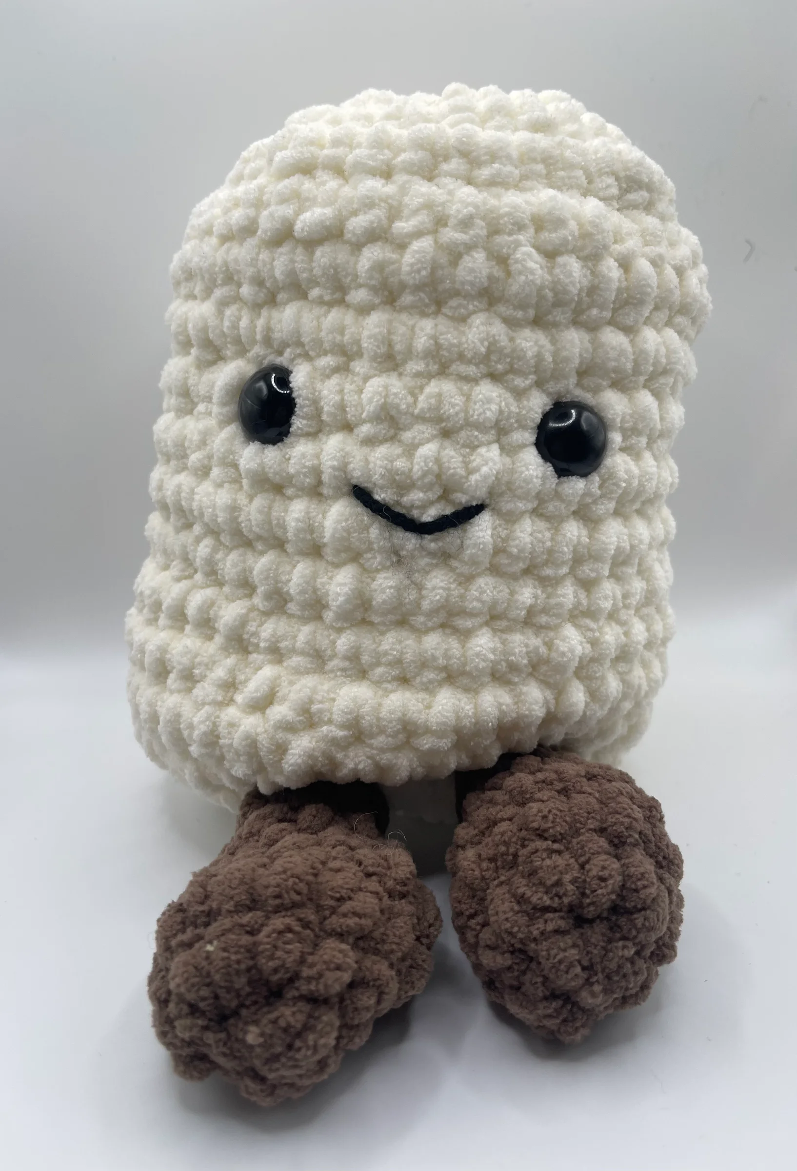 Crocheted from chunky white yarn and detailed with large glossy black safety eyes and a small, happy black stitched smile.